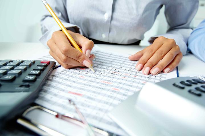 Accountant is doing bank reconciliation with paper and pen.